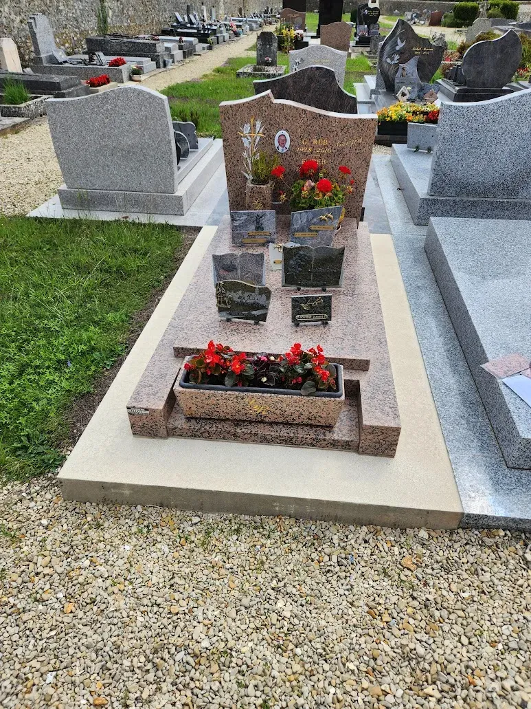 Monument funéraire en granit rose fleuri dans un cimetière.