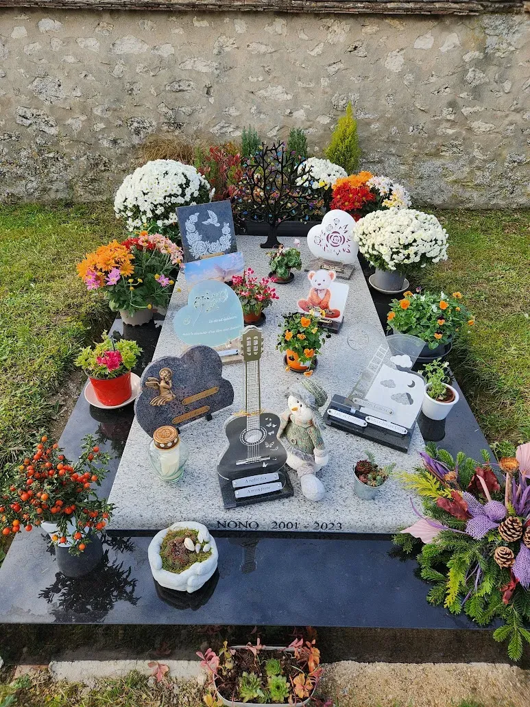 Sépulture personnalisée couverte d'hommages, de fleurs et d'objets.