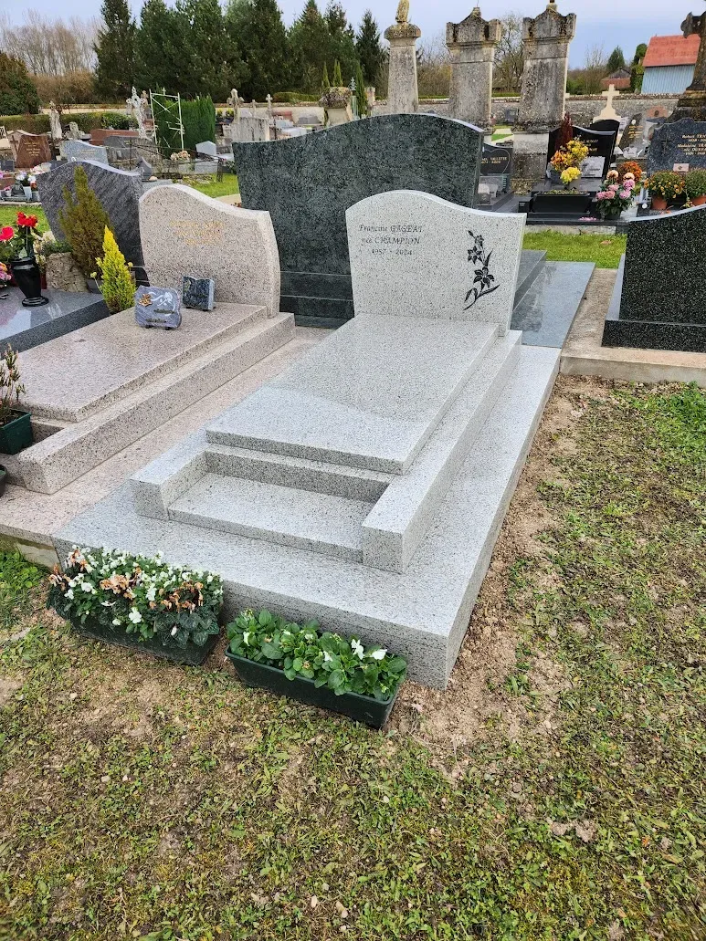 Monument funéraire moderne en granit gris clair avec gravure florale.