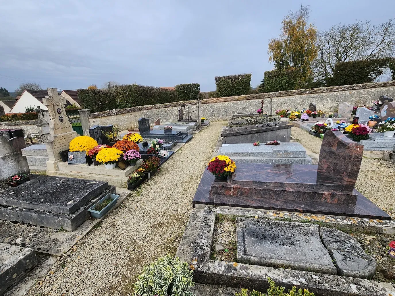 Allée d'un cimetière bordée de sépultures et de plaques funéraires.