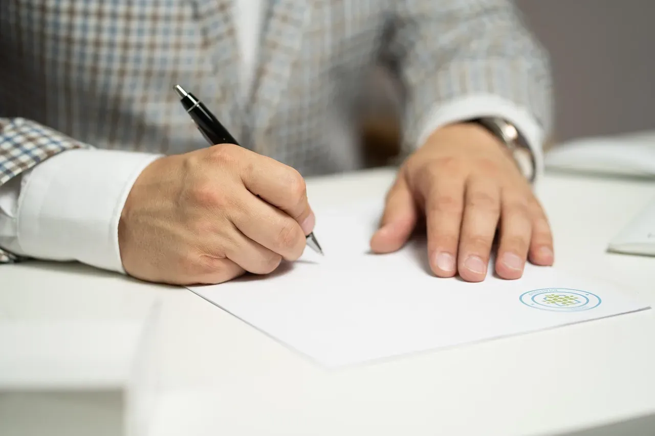 Main d'un homme écrivant un document officiel avec un stylo-bille.