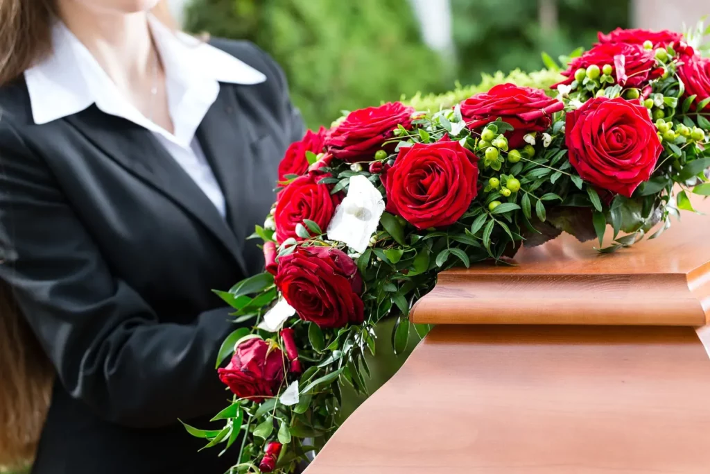 Arrangement floral de roses rouges déposé sur un cercueil en bois.